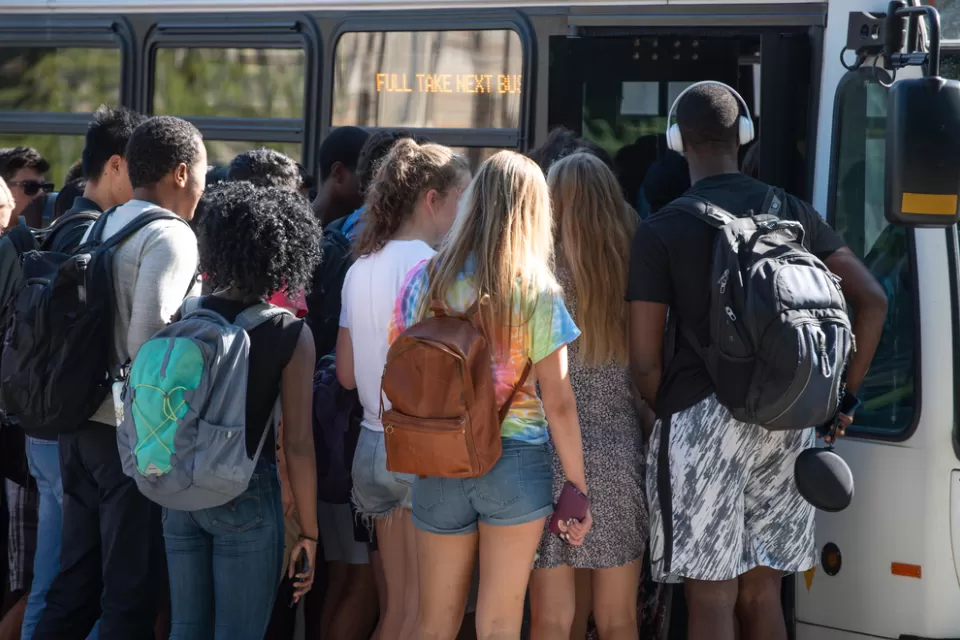Group of diverse college students boarding crowded bus